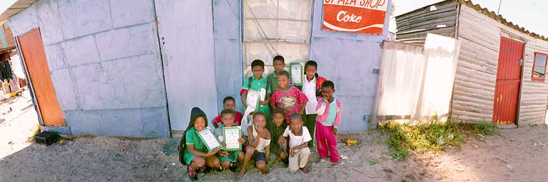 Khayelitsha - Kinder mit Schulbüchern vor Wellblechhütte